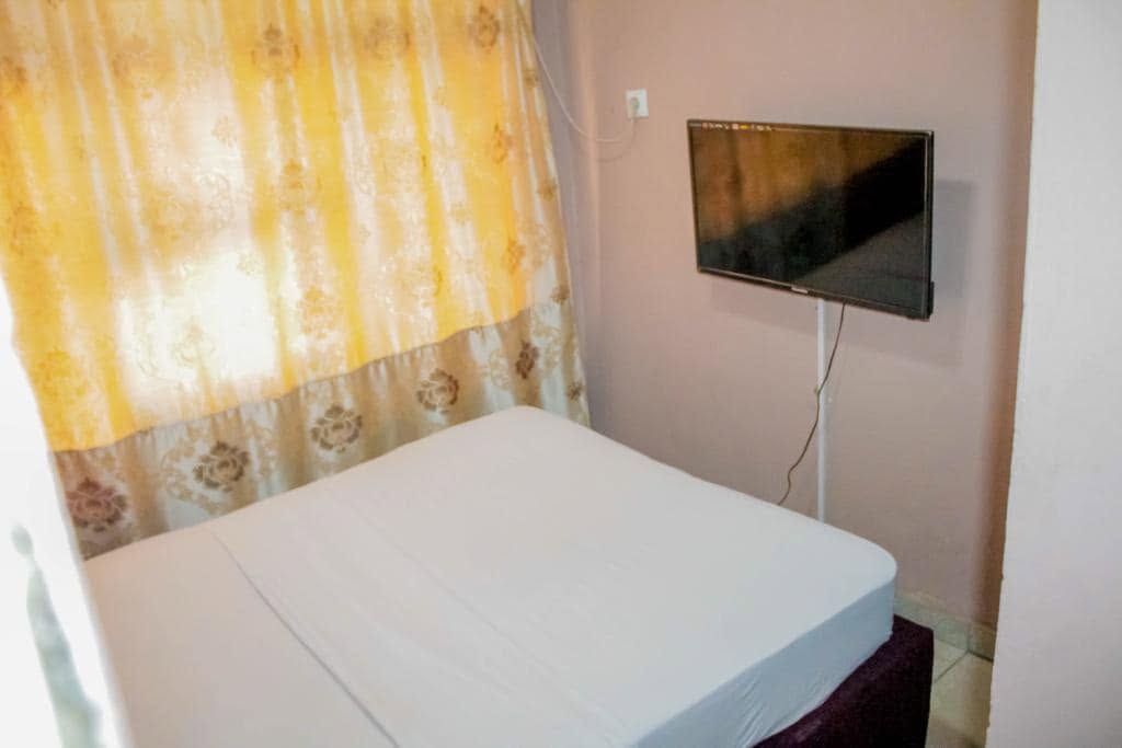 Une chambre lumineuse avec rideaux dorés et télévision